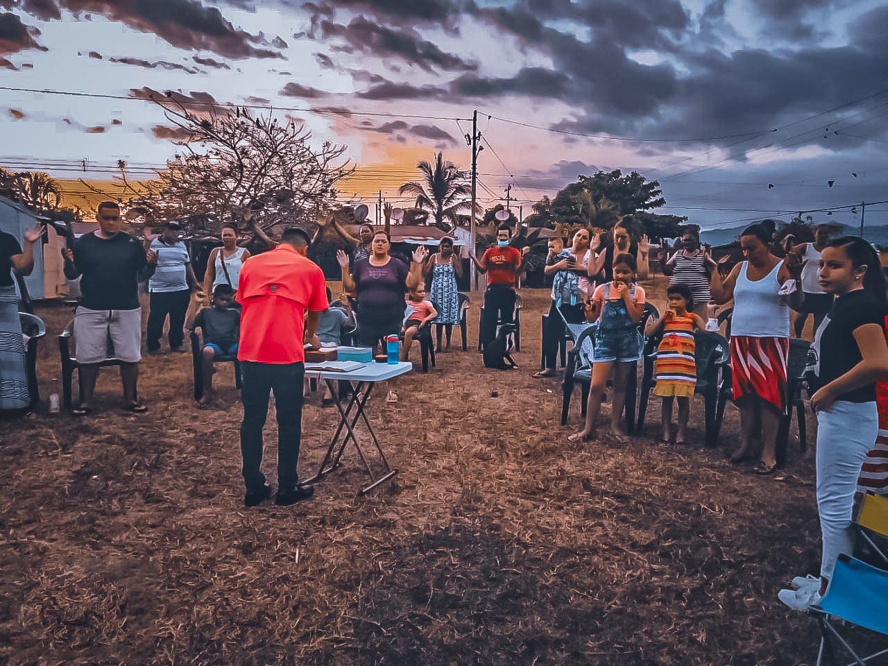 Grupo reunido al aire libre al atardecer, con el cielo cargado de nubes sobre el horizonte
