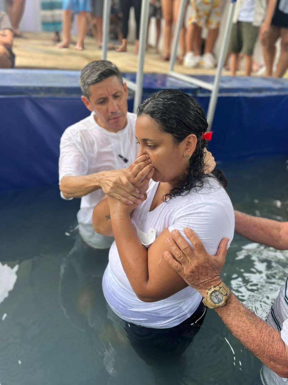 El pastor Roberto sostiene a una mujer durante su bautismo, ambos de pie dentro del agua
