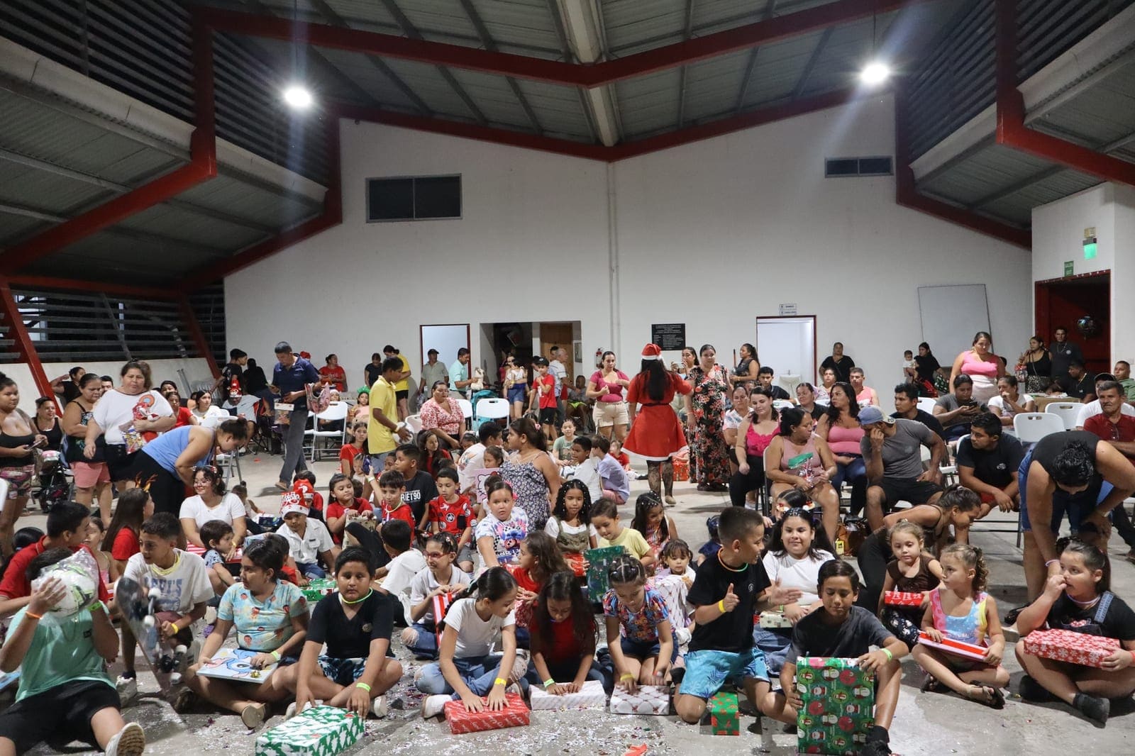 Un salón lleno de niños sentados en el piso durante una actividad del club
